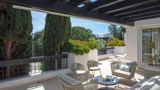 A covered outdoor seating area with wicker furniture and a glass door leading to a balcony. - Exclusive 2BD Apartment With Private Terrace in Marbella Incosol (Marbella)