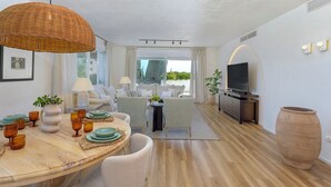 A modern living room with a dining area, a sofa set, a TV, and a large vase. - Exclusive 2BD Apartment With Private Terrace in Marbella Incosol (Marbella)