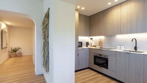 A modern kitchen with wooden cabinets, a microwave, a sink, and a stove. - Exclusive 2BD Apartment With Private Terrace in Marbella Incosol (Marbella)