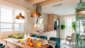 A modern kitchen with wooden cabinets, a built-in oven, and a dining area with a wooden table and blue chairs. - Fantastic 3 Bd 3 Bth Apartm With Comunnal Terrace Carmen San Ignacio II (Granada)