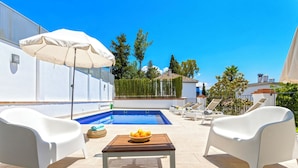 A poolside area with a pool, white lounge chairs, a table with a bowl of fruit, and a large umbrella. - Fantastic 3 Bd 3 Bth Apartm With Comunnal Terrace Carmen San Ignacio II (Granada)