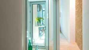 Ein Flur mit Glastrennwand, einer grünen Flasche und einem transparenten Glasobjekt auf dem Boden.