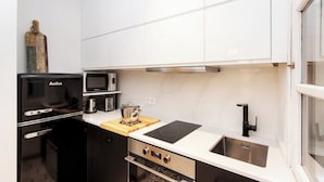Une cuisine moderne avec des meubles blancs, un réfrigérateur noir, un four à micro-ondes, une cuisinière et un évier.