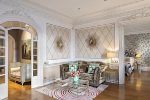 A spacious living room with a large sofa, a coffee table, and a decorative mirror.