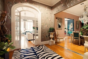 A room with a zebra-patterned rug, a chandelier, and a dining area with a table and chairs.