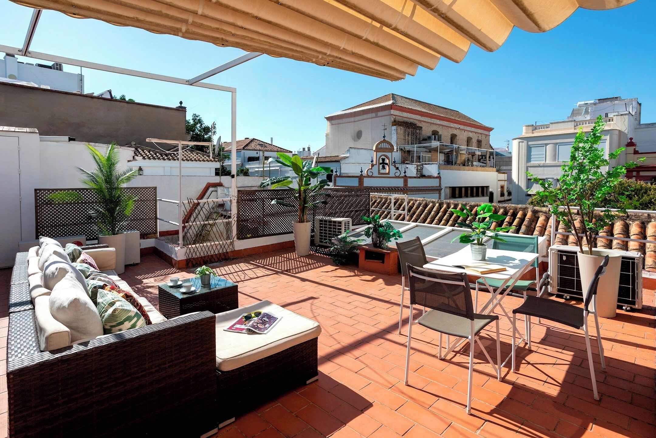 A rooftop terrace with outdoor seating, a pool, and a view of surrounding buildings.