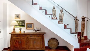 Eine Treppe mit einem Holzkabinett, einer Lampe, einem Gemälde und einer Skulptur.