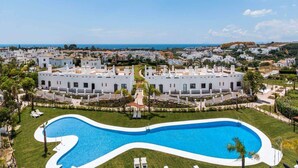Un complexe hôtelier doté d’une grande piscine, de bâtiments blancs et offrant une vue sur la mer.