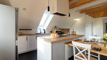 Una cocina moderna con una isla central, armarios blancos y un tragaluz.