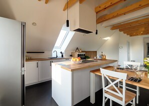 A modern kitchen with a central island, white cabinetry, and a skylight. - Hiša Janko (Dolenjske Toplice)