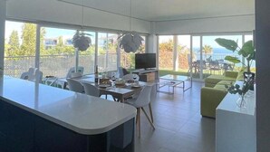 A modern kitchen with a central island, dining area with chairs, and a large window overlooking a garden. - Luxury Apartment With Sea View (Benalmádena)