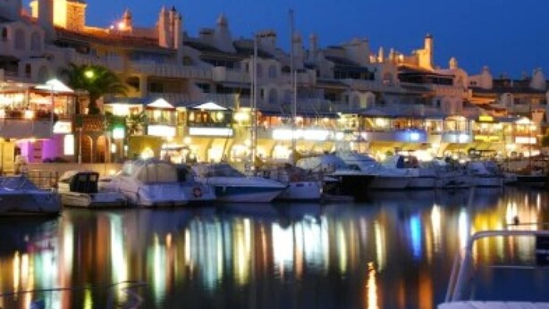 A marina with boats docked, a waterfront promenade, and buildings with illuminated signs. - Luxury Apartment With Sea View (Benalmádena)