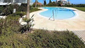 A modern hotel with a pool, palm trees, and a clear blue sky. - Luxury Apartment With Sea View (Benalmádena)