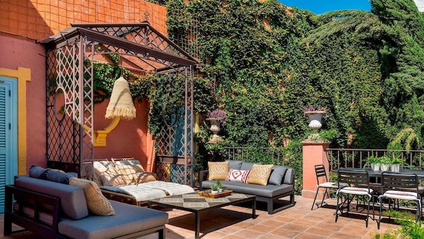Un patio exterior con un sofá, una mesa baja y un comedor.