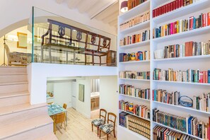 A multi-level interior with a staircase, a dining area, and a large bookshelf filled with books. - Modern Apartment 2 Bd 2 Bth Near the Cathedral Catedral V (Seville)