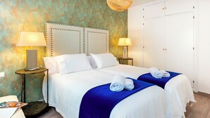 A hotel room with a large bed, two bedside tables with lamps, a wardrobe, and a textured wall. - Magnificent 3 Bd 2 Bathrooms in Plaza de las Flores (Málaga)
