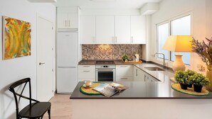 A modern kitchen with white cabinetry, a built-in oven, and a dining area with a table and chairs. - Magnificent 3 Bd 2 Bathrooms in Plaza de las Flores (Málaga)