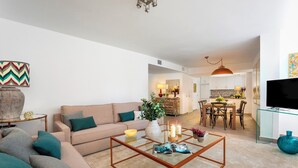 A living room with a sofa, coffee table, and a dining area with chairs and a table. - Magnificent 3 Bd 2 Bathrooms in Plaza de las Flores (Málaga)