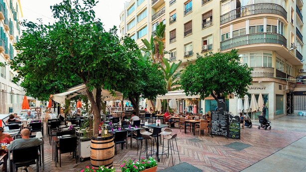 An outdoor cafe area with tables and chairs, surrounded by trees and buildings. - Magnificent 3 Bd 2 Bathrooms in Plaza de las Flores (Málaga)