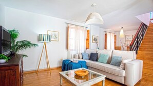 A living room with a sofa, a coffee table, a lamp, a TV, and a staircase. - Modern Confortable 3 Bd Duplex Great Location Piedra Santa (Granada)