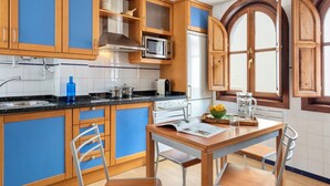 A kitchen with wooden cabinets, a stove, a microwave, and a window with wooden shutters. - Modern Confortable 3 Bd Duplex Great Location Piedra Santa (Granada)