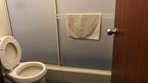 Een badkamer met een toilet, een handdoek aan de muur en een houten deur.