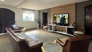 A spacious living room with leather sofas, a coffee table, and a flat-screen TV mounted on the wall. - Beautiful Mairiporã Farm with Beach Tennis Court (Mairiporã)