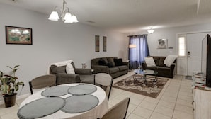 Ein Wohnzimmer mit Esstisch, zwei Sofas, einem Couchtisch und einem Fernseher.