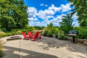 An outdoor patio with red chairs, a table, and a barbecue grill.