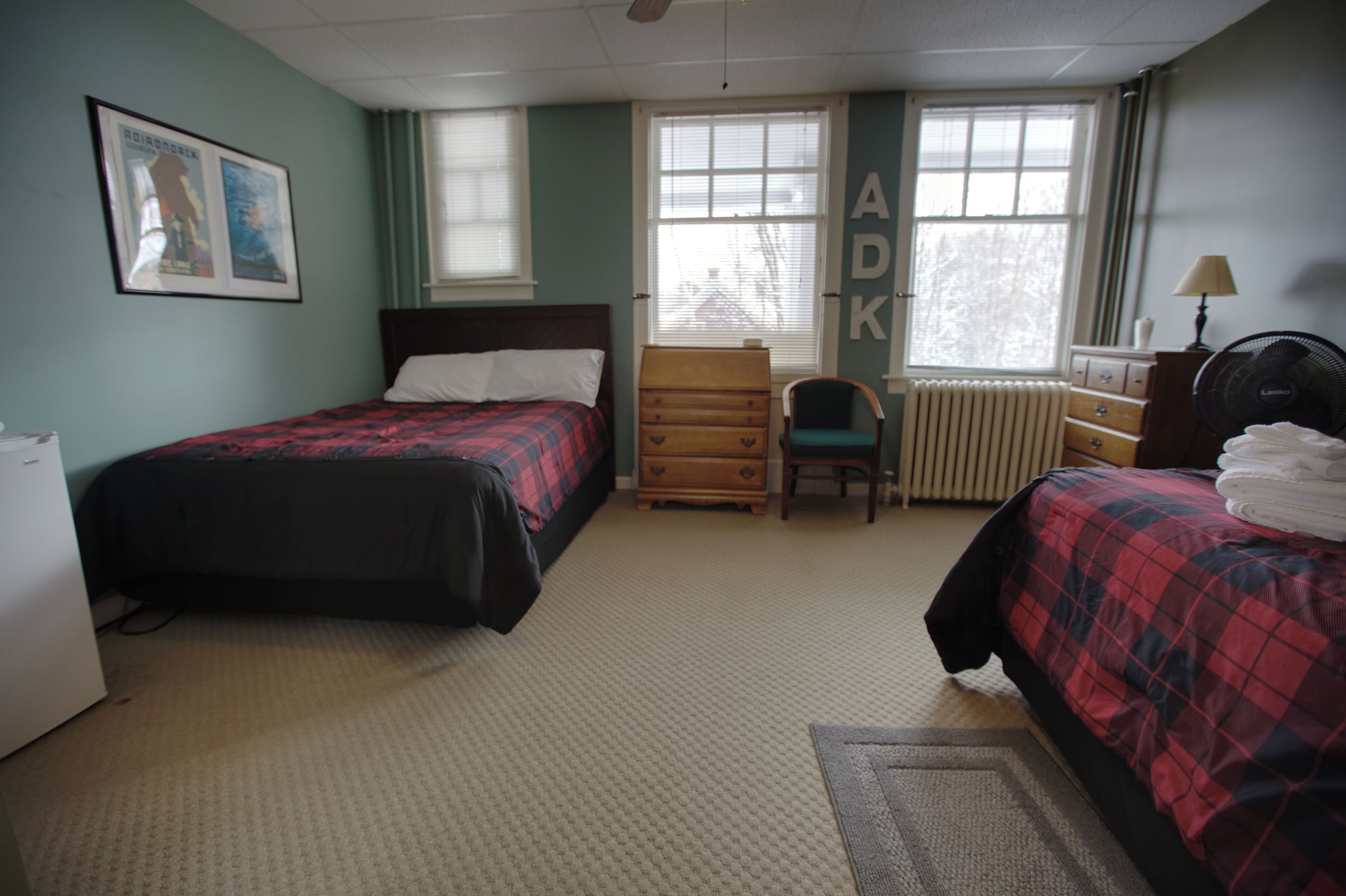 A bedroom with two beds, a dresser, a chair, and a radiator.