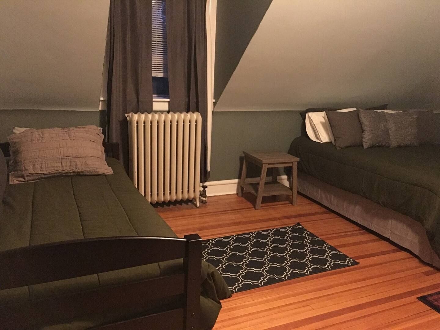 Una habitación pequeña y acogedora con una cama, un sofá, un radiador y una mesita.