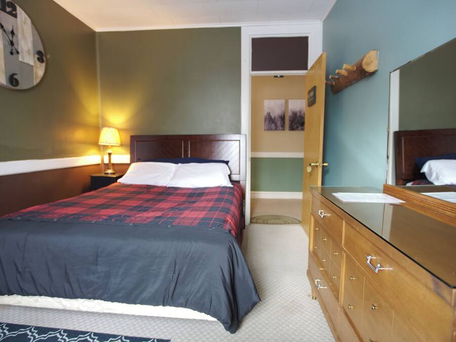 A hotel room with a bed, a nightstand with a lamp, a dresser, and a mirror.