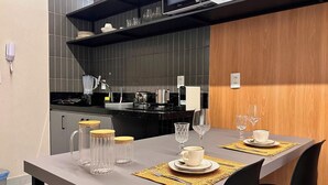 A modern kitchen with a dining area set for two. - Simple Smart - LikeHome Hospedagens (João Pessoa)