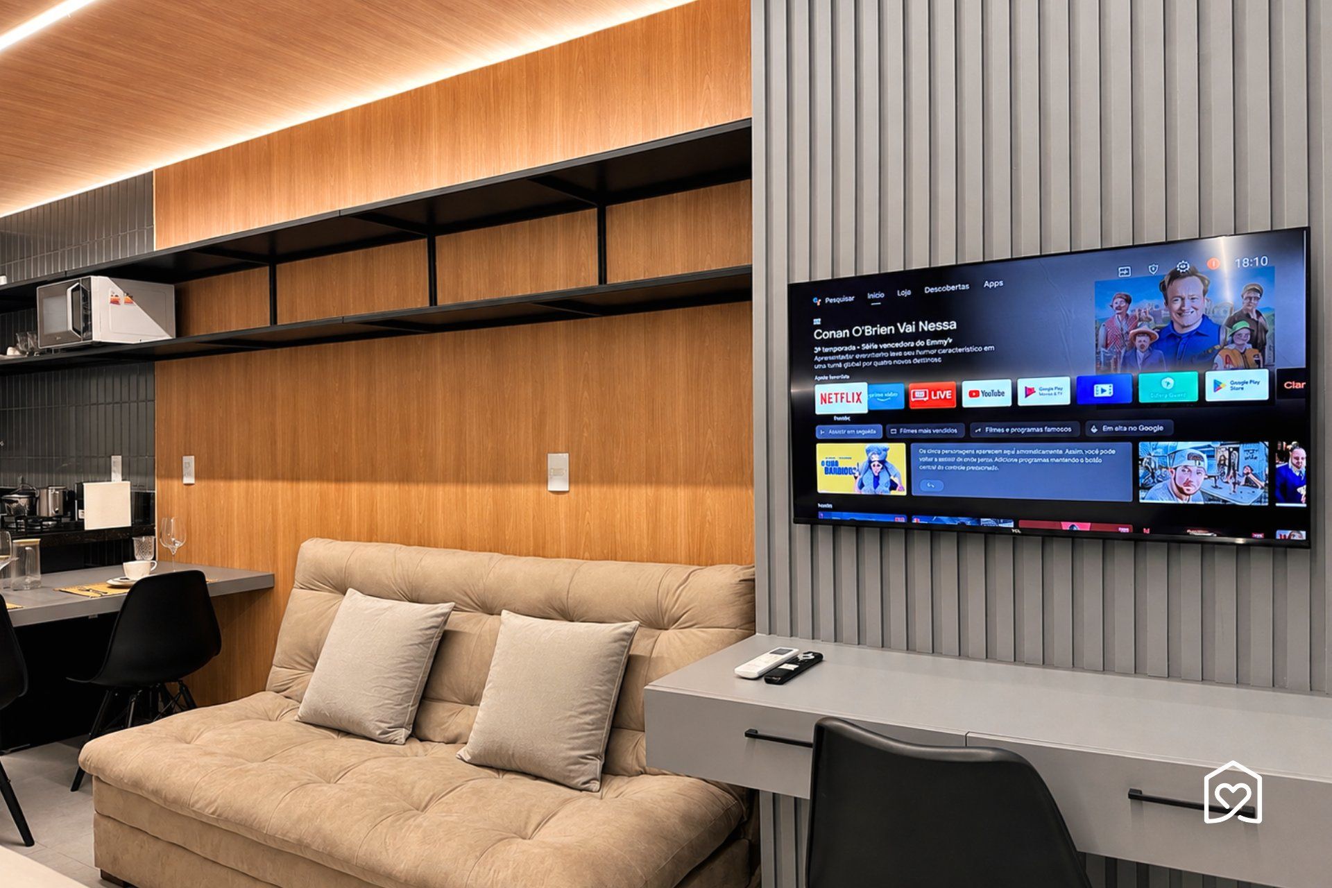 Una sala moderna con sofá, escritorio y televisor montado que muestra varios servicios de transmisión.