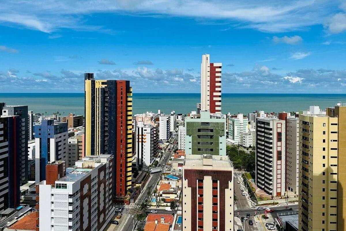 A cityscape with tall buildings, a clear sky, and a view of the ocean.