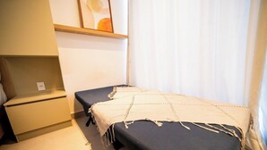 A small, private room with a single bed, a bedside table, and a wall-mounted shelf. - Simple Smart - LikeHome Hospedagens (João Pessoa)