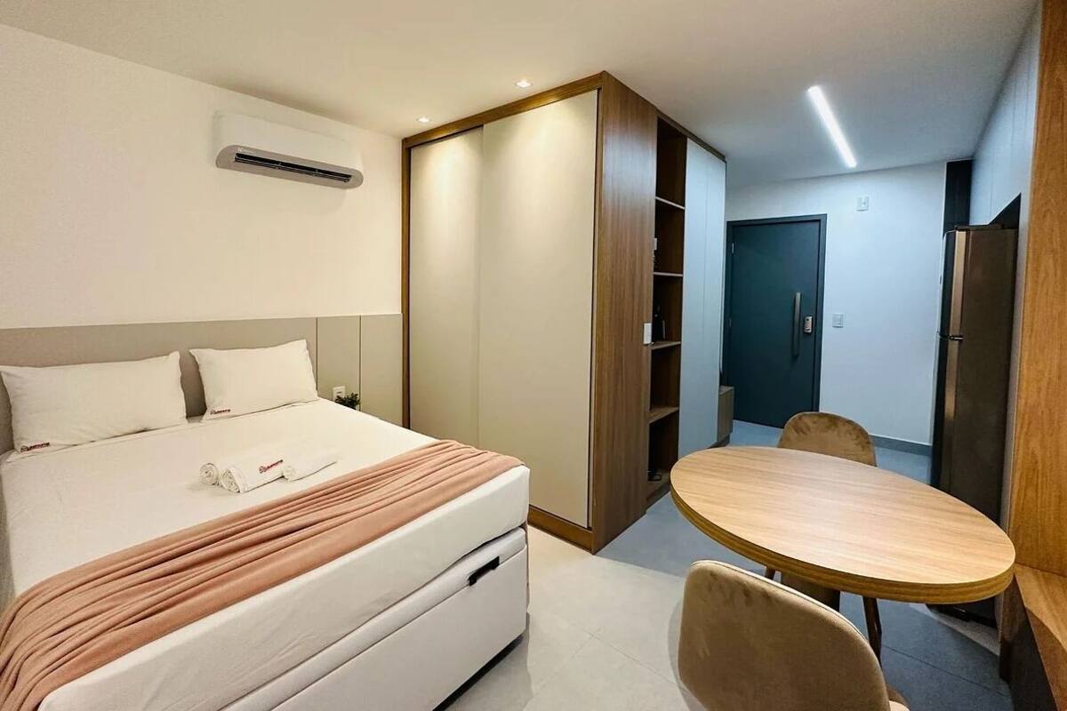 A hotel room with a bed, a round wooden table, and a wardrobe.