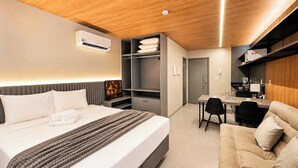 A hotel room with a bed, bedside table, wardrobe, and a kitchenette area. - Simple Smart - LikeHome Hospedagens (João Pessoa)