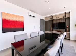A modern dining area with a glass table, grey chairs, and a red abstract painting on the wall. - Simple Smart - LikeHome Hospedagens (João Pessoa)