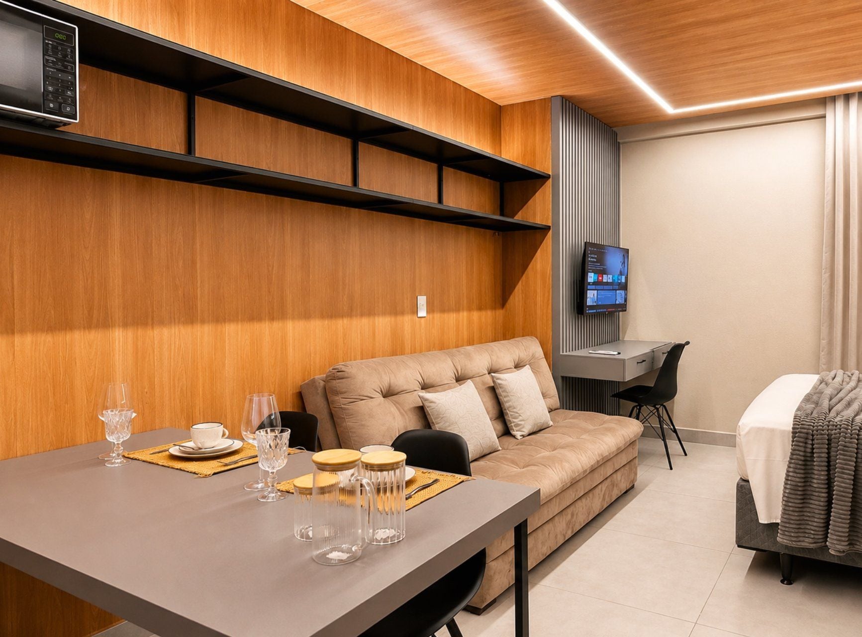 Une chambre d’hôtel moderne équipée d’un canapé, d’un bureau, d’une télévision et d’un coin repas avec une table et des chaises.