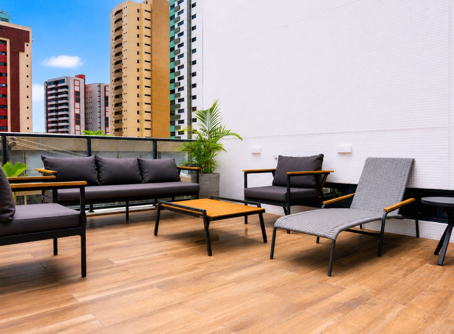 A rooftop lounge with a sofa, chairs, a small table, and a potted plant.