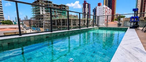 A rooftop pool with a view of a cityscape, including a construction site and high-rise buildings.