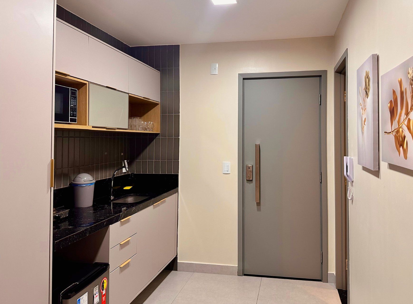 A compact kitchen with a refrigerator, a microwave, and a sink.