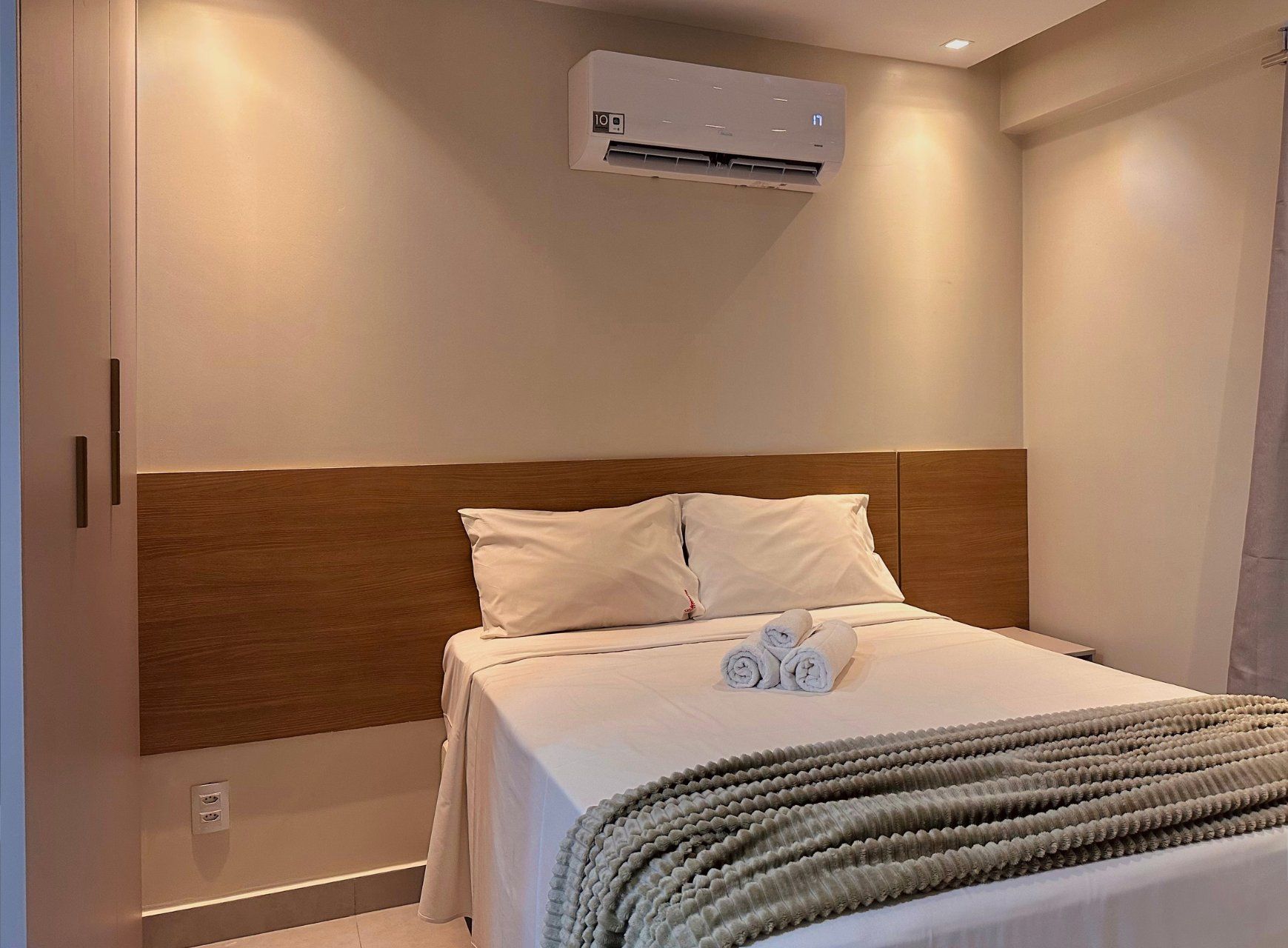 Ein Hotelzimmer mit einem Bett, einem Kopfteil, einer Klimaanlage und einem Handtuch auf dem Bett.