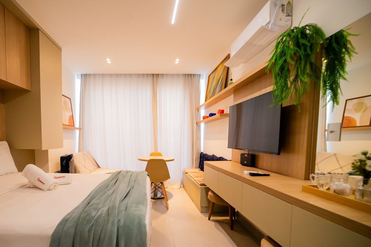 Une chambre d’hôtel comprenant un lit, une table de chevet, une télévision et un bureau avec une chaise.