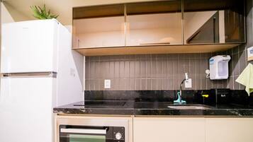 A kitchen with a white refrigerator, a dishwasher, a sink with a faucet, and a tiled backsplash.