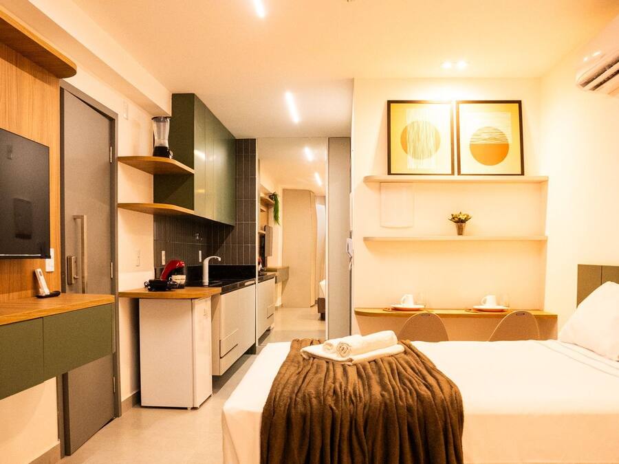 Een hotelkamer met een bed, een televisie, een kitchenette en een kleine eethoek.
