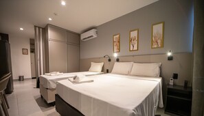 Habitación de hotel con dos camas, un armario, un equipo de aire acondicionado e iluminación empotrada.