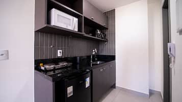 A modern kitchen with grey cabinets, a black countertop, a microwave, and a built-in dishwasher.