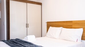 A hotel room with a bed, a wooden headboard, a wardrobe, and a control panel on the wall. - Simple Smart - LikeHome Hospedagens (João Pessoa)